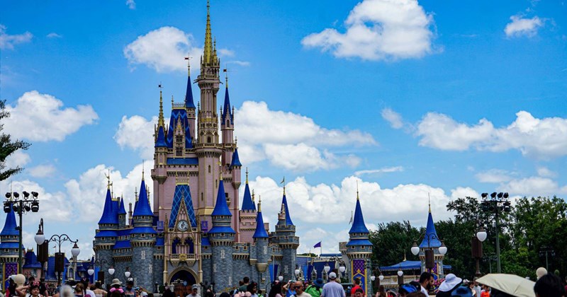 A crowd of people standing in front of the Disney World castle