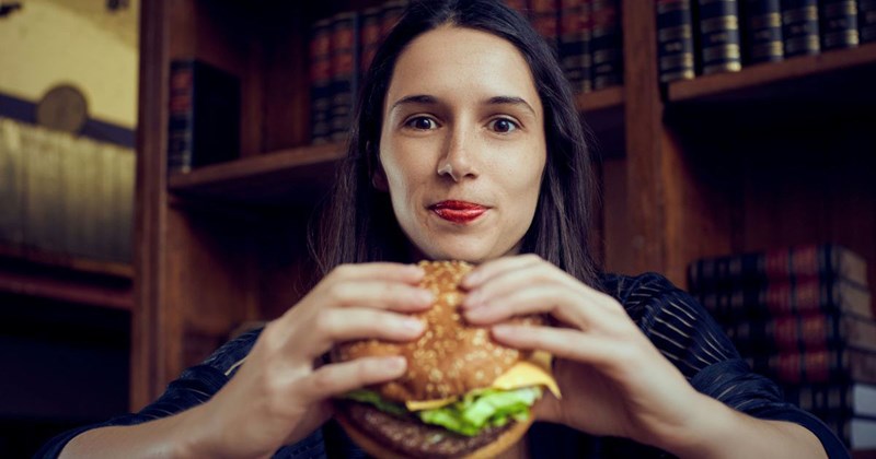 A woman eats a cheeseburger in a study library office