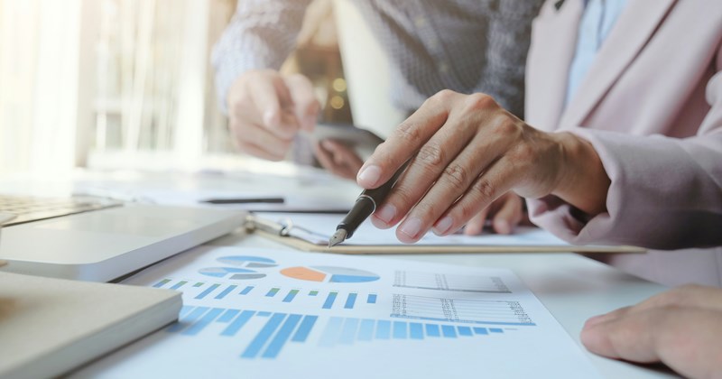 An employee points at a report while the boss critiques it