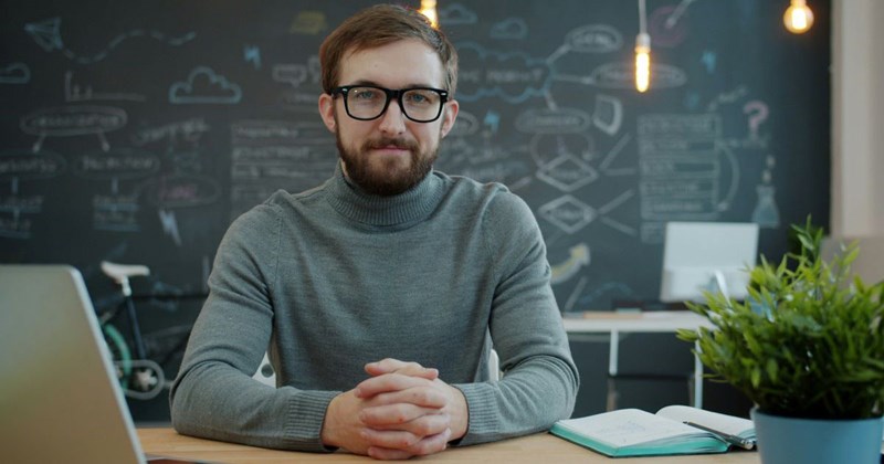 Man wearing glasses sits at desk in office