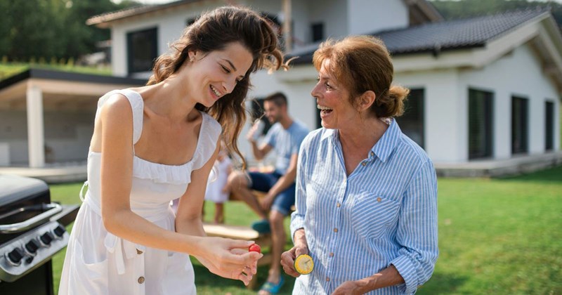 Mother-in-law and daughter-in-law talk at outdoor barbeque