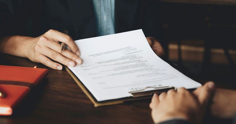 Recruiter looking over job applicant's resume while interviewing him